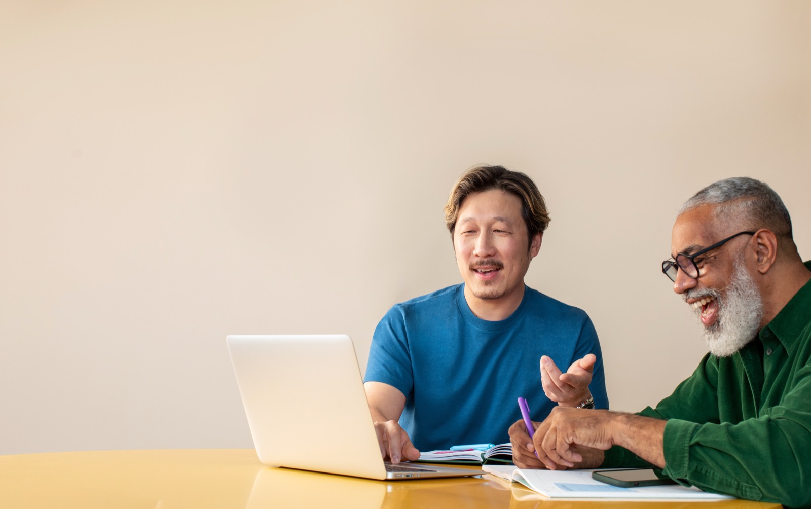 Two colleagues laughing while going over a campaign on a laptop together.